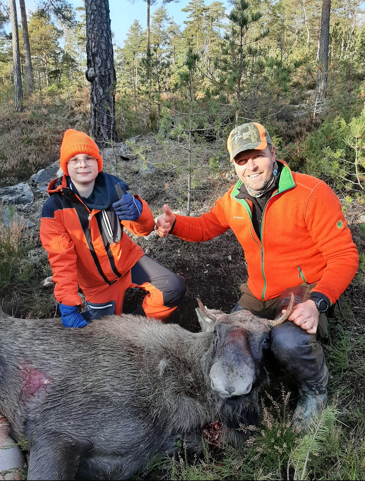 To jegere sammen med en felt elg i skogen